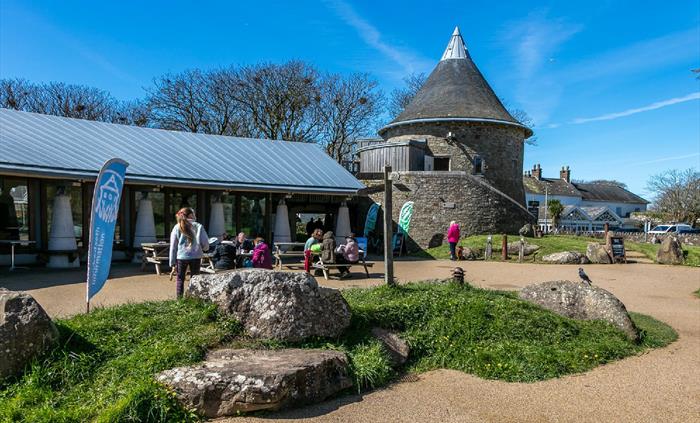 View of outside Oriel y Parc including gallery tower and visitors outside on picnic benches